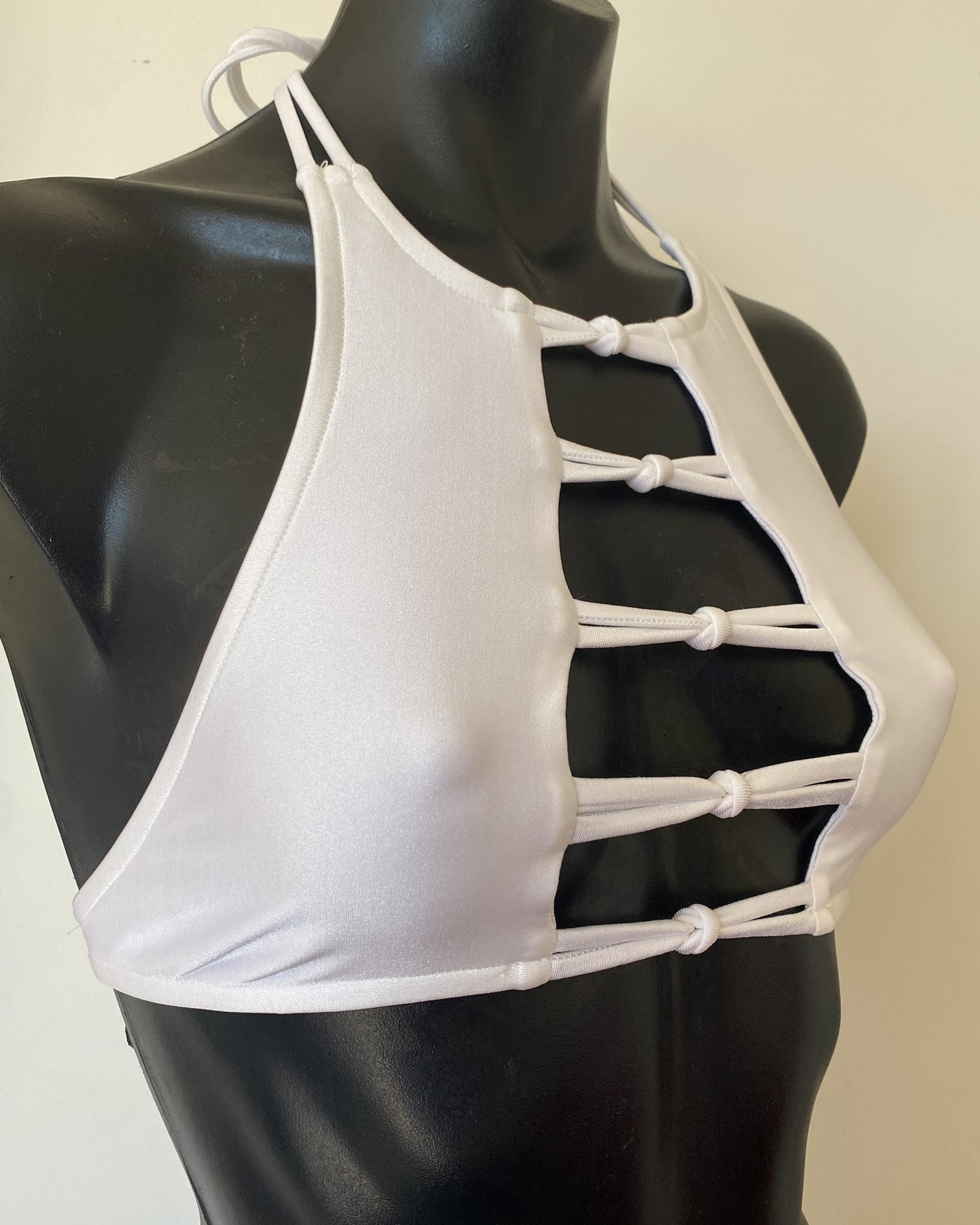 Side profile of the Miss Maneater white designer bikini crop top showing sculpted halter neckline and smooth nylon lycra finish.