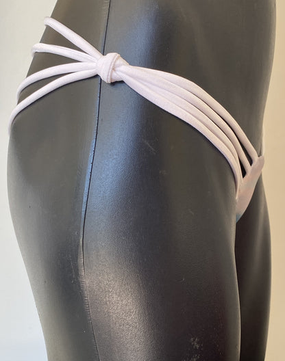 Close up side profile of MissManeater SHARKskin strap side bikini pant showing tied knot and strap tension on hips Australian made designer swimwear
